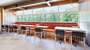 Un restaurante moderno con un amplio banco de madera y varias mesas y sillas.