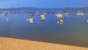 A calm body of water with several boats anchored, a sandy beach in the foreground, and distant hills under a clear sky. - Classic Family Tahoe Cabin - West Shore Bliss! (Tahoma)