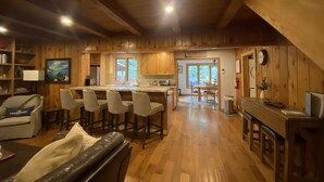 A cozy cabin interior with wooden walls, a bar area, and a dining space. - Classic Family Tahoe Cabin - West Shore Bliss! (Tahoma)