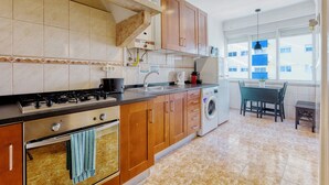 Eine moderne Küche mit Holzschränken, einem Gasherd, einem Backofen und einer Waschmaschine.
