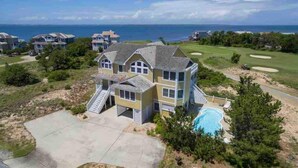 A large two-story house with a swimming pool, located near a golf course and the ocean. - Destination-OBX Soundfront, 8 bdrm, 10 bth, elavator, pool, hot tub, game room (Nags Head)