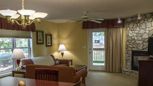 A cozy living room with a fireplace, a dining area with a table and chairs, and a seating area with a sofa and lamps.