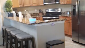 Una cocina moderna con armarios de madera, electrodomésticos de acero inoxidable y encimera de granito.