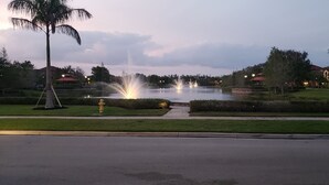 Un parque con una fuente, una palmera y un edificio de techo rojo al fondo.