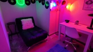 Una habitación con un sofá de cuero negro, un escritorio blanco y una alfombra azul.