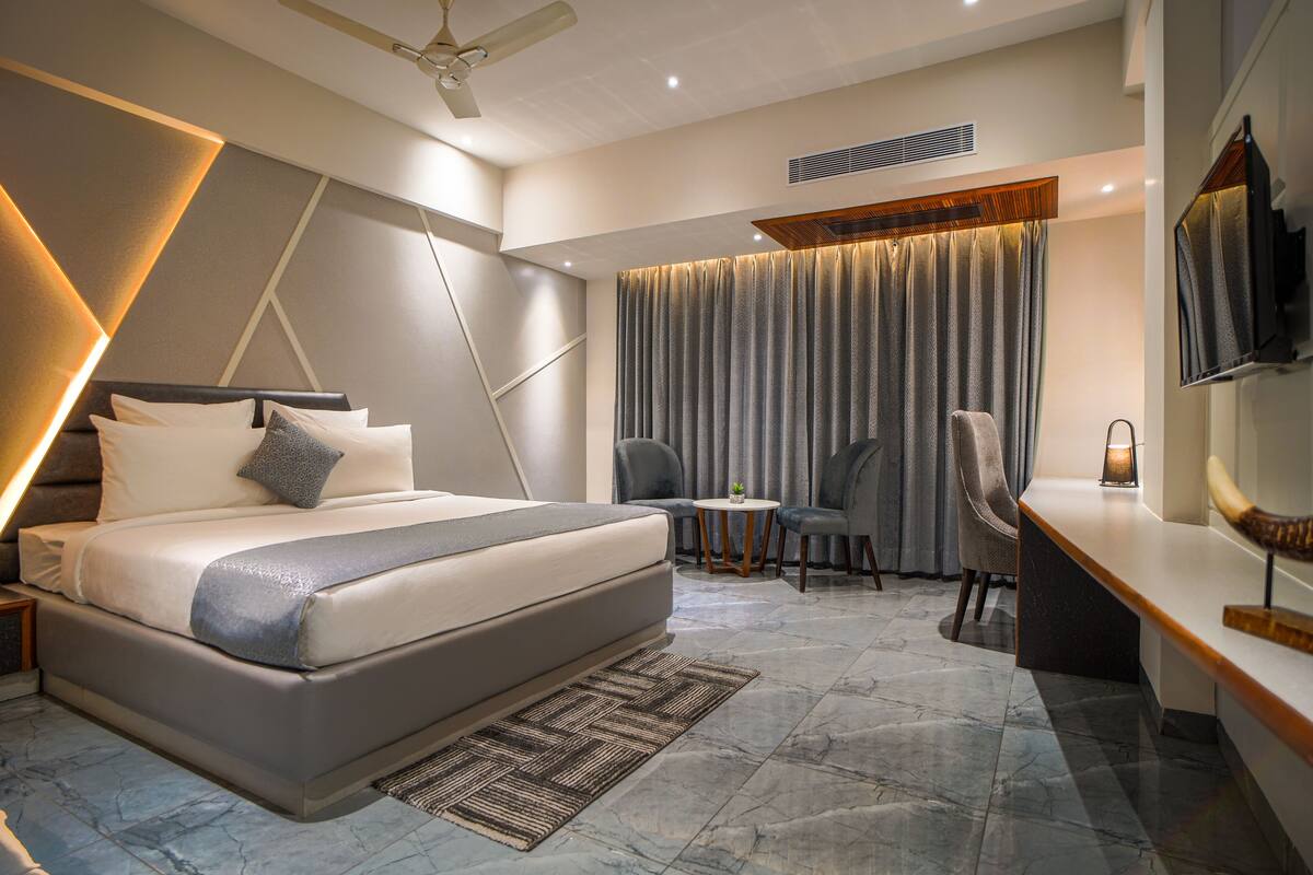 A modern hotel room with a large bed, a desk, and a chair.