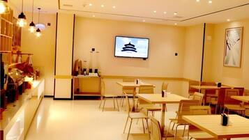 A modern restaurant with a counter, tables, and chairs.