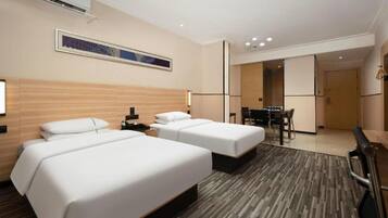 A hotel room with two beds, a desk, and a dining area.