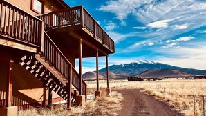 A two-story building with a wooden balcony and a dirt road leading to a mountainous landscape. - Beautiful Views! Home near Grand Canyon, Flagstaff (Flagstaff)