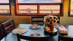 A dining table with woven placemats, a vase with sunflowers, and a view of a mountain through a window. - Beautiful Views! Home near Grand Canyon, Flagstaff (Flagstaff)