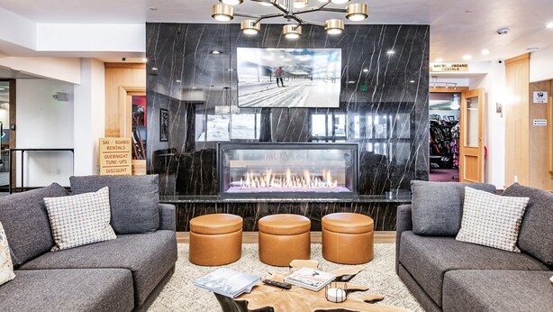 En moderne lobby med pejs, grå sofaer og et stort tv.