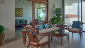 A spacious living room with a large sliding glass door leading to a balcony, wooden furniture, and a potted plant.