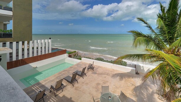 A poolside area with lounge chairs and a view of the ocean.