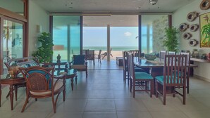 A spacious dining area with a view of the ocean, featuring wooden furniture and ceiling fans.