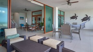 A spacious living area with wicker furniture, a hammock, and a ceiling fan.