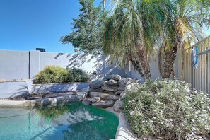 A swimming pool with a clear blue water feature, surrounded by rocks and plants, and a palm tree. - Scottsdale Kierland 3 Bdrm with Spakling Pool! (Scottsdale)