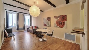 Un espace repas comprenant une table ronde et des chaises, un luminaire suspendu et des œuvres d’art accrochées aux murs.