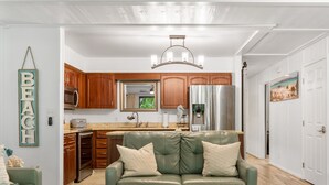 Una cucina moderna con mobili in legno, elettrodomestici in acciaio inossidabile e un divano in pelle verde nella zona living.