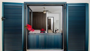 A room with a bed, a ceiling fan, and a view of a hallway with a door.
