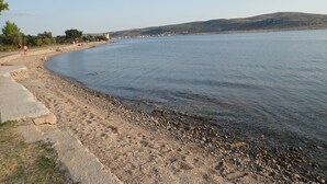 A pebbled beach with a clear view of the water and distant hills. - Vacation home in traditional style in a very quiet location (Starigrad Paklenica)