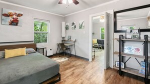 A bedroom with a bed, desk, and a ceiling fan.