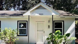 A small, single-story house with a white exterior, a front door, and two windows.