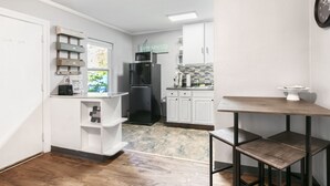 A compact kitchen with white cabinets, a black refrigerator, and a small dining table.