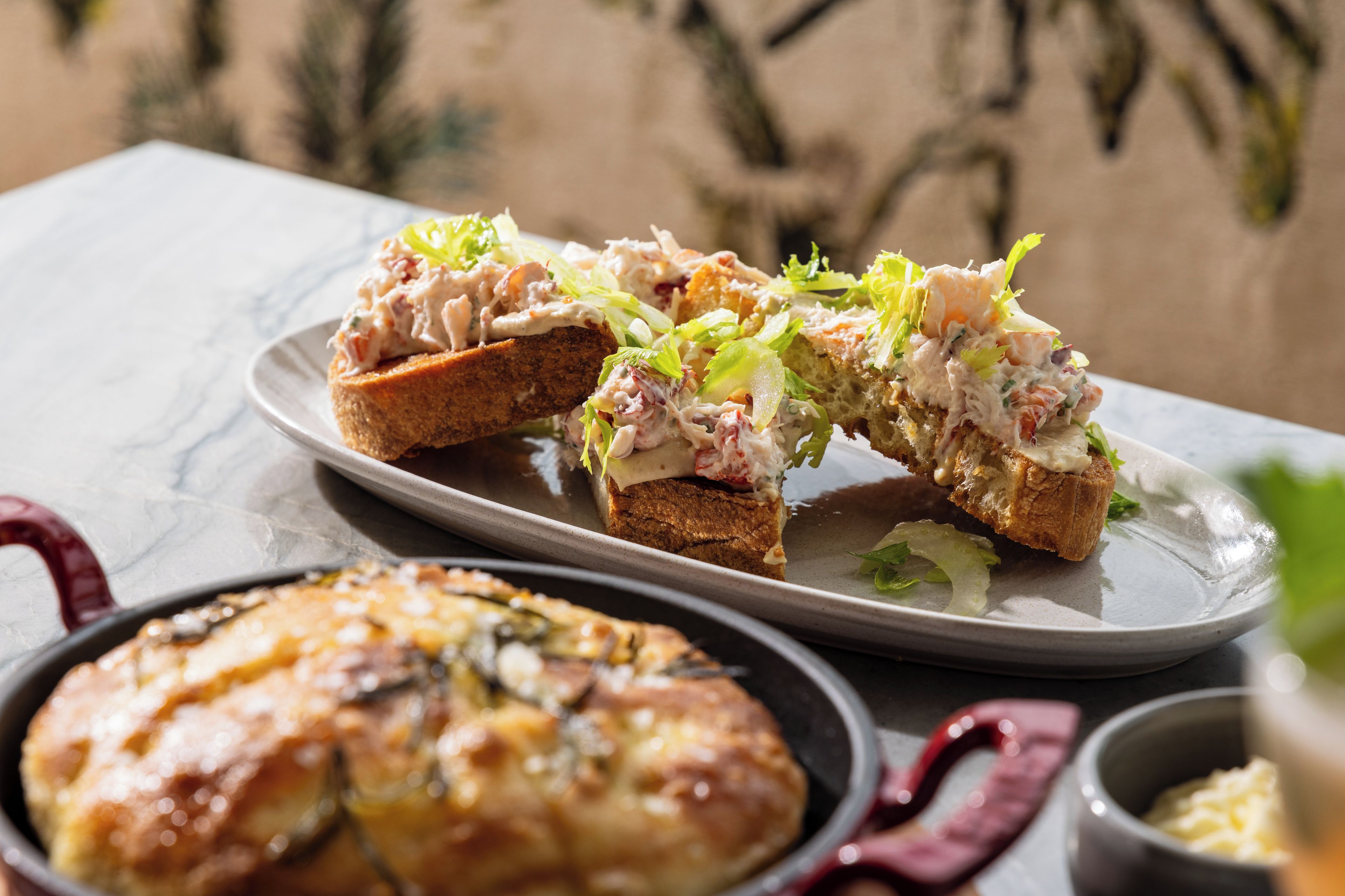 A plate of food with bread and salad, and a pie on a table.