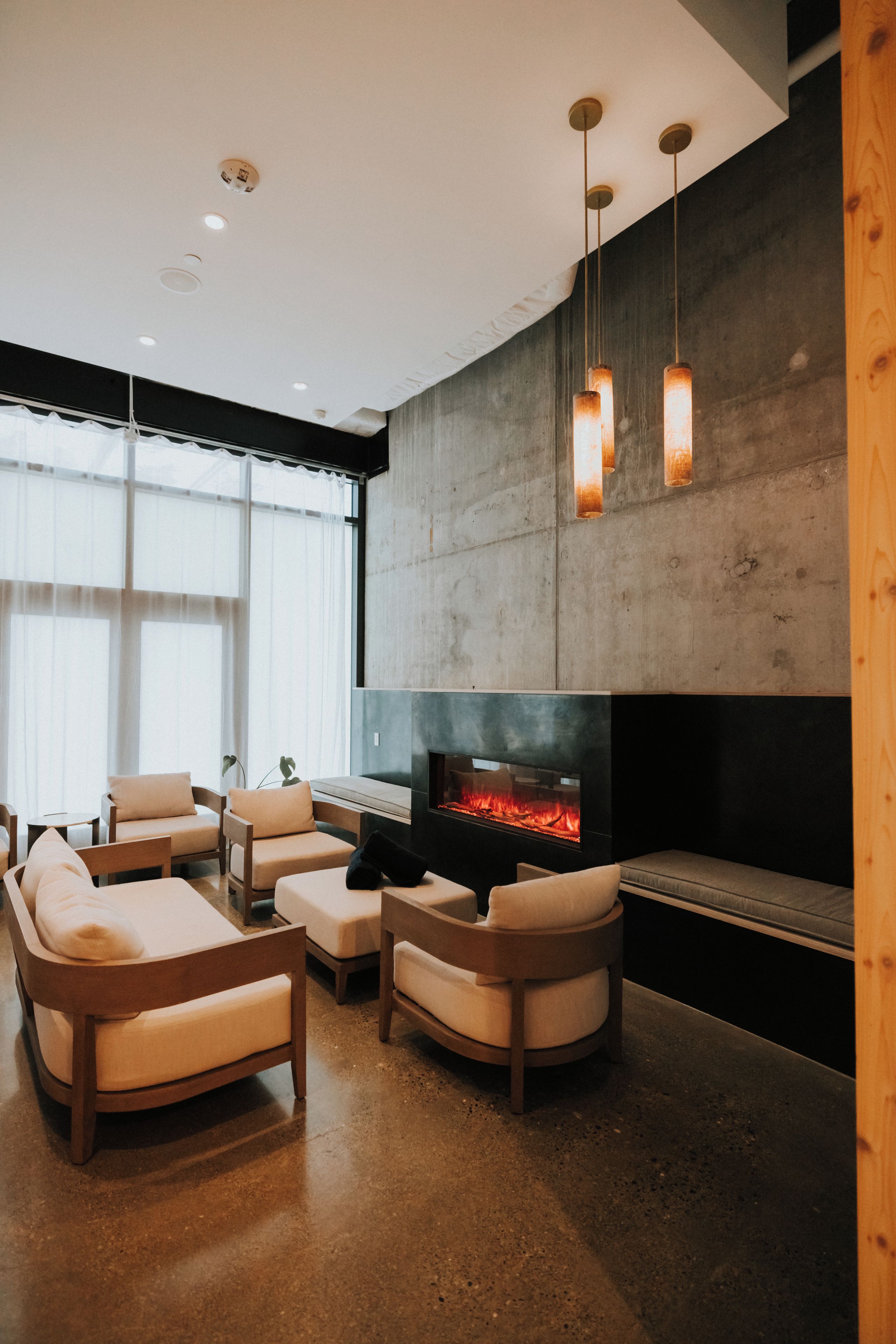 A modern living room with a fireplace, sofas, and a large window.
