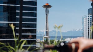 A view of the Space Needle with a modern building in the foreground and mountains in the background. - Level Seattle Downtown - South Lake Union (Seattle)