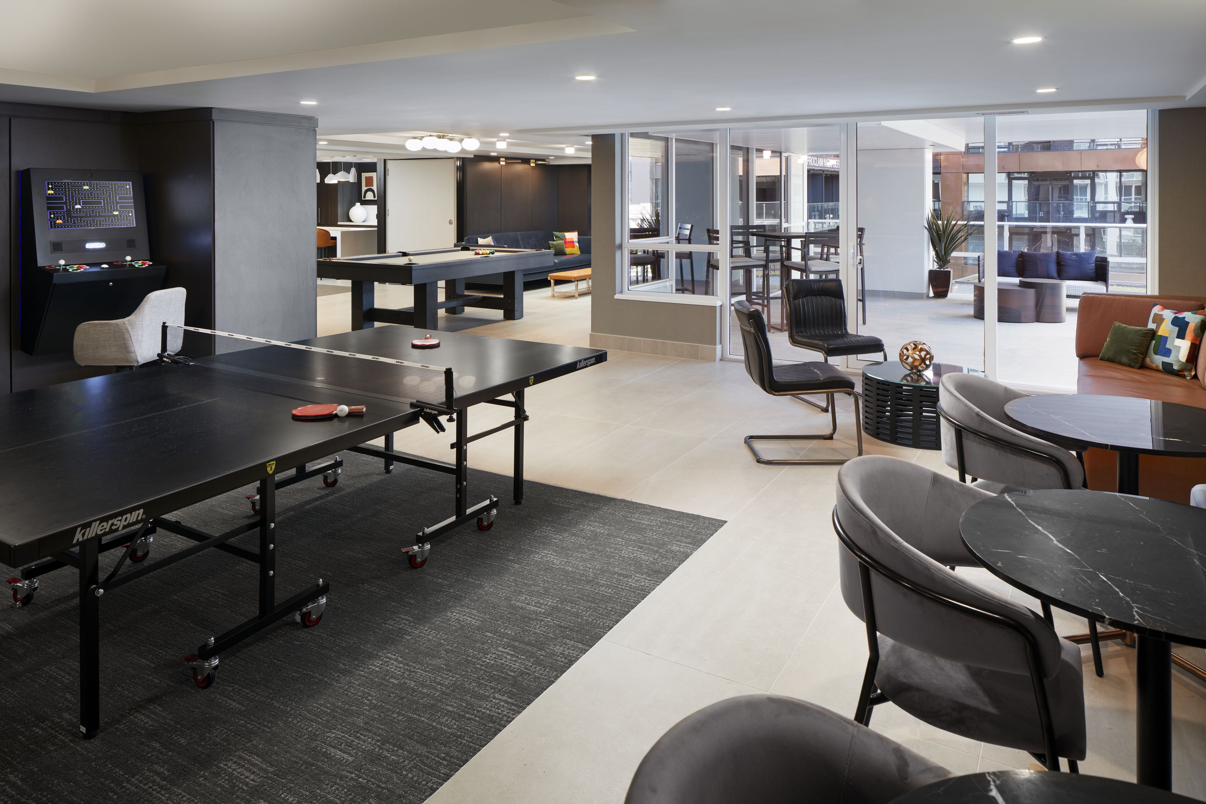 Un área recreativa moderna con mesa de billar, mesa de ping pong y asientos.