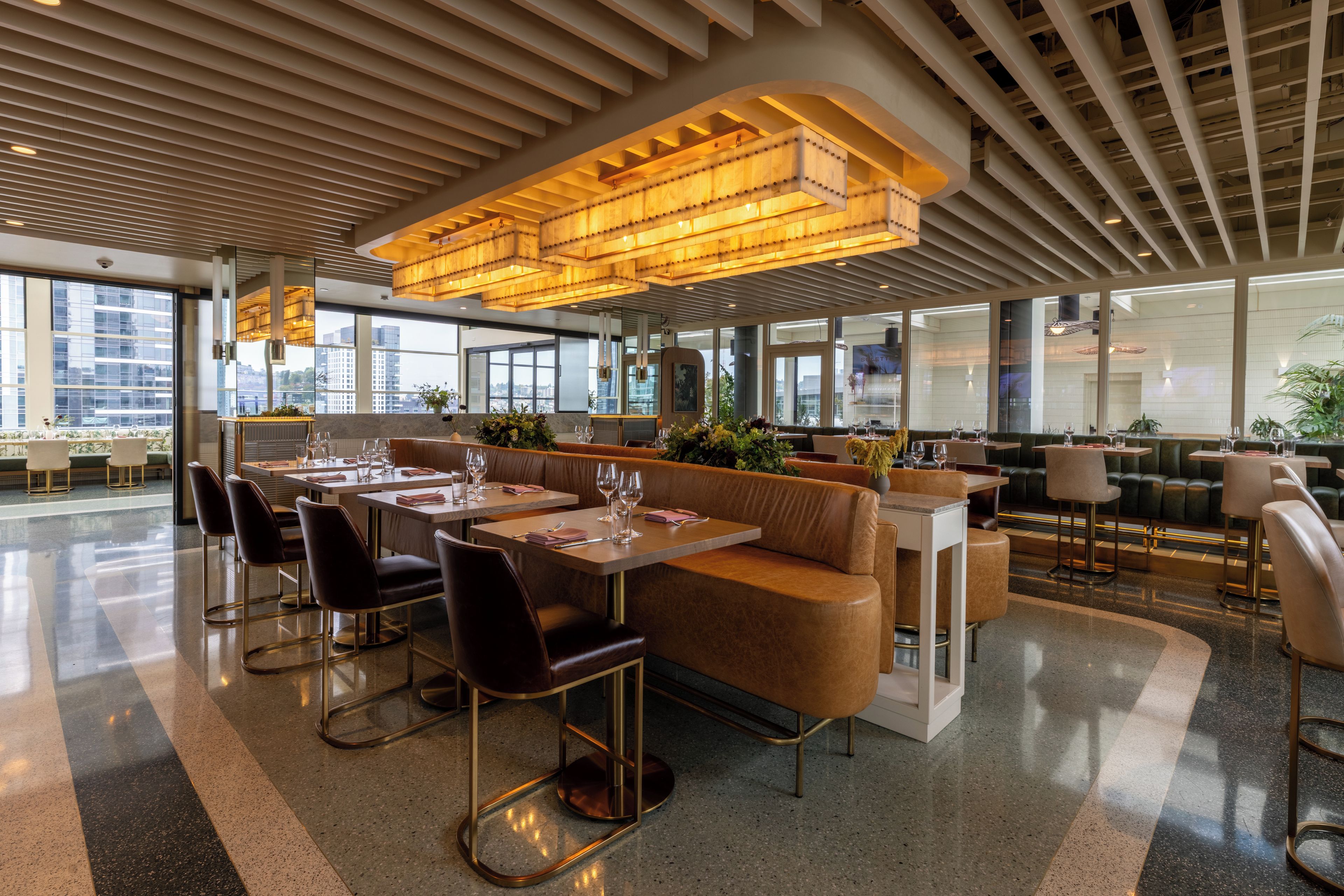 A modern restaurant with high ceilings, large windows, and a variety of seating options including tables and booths.