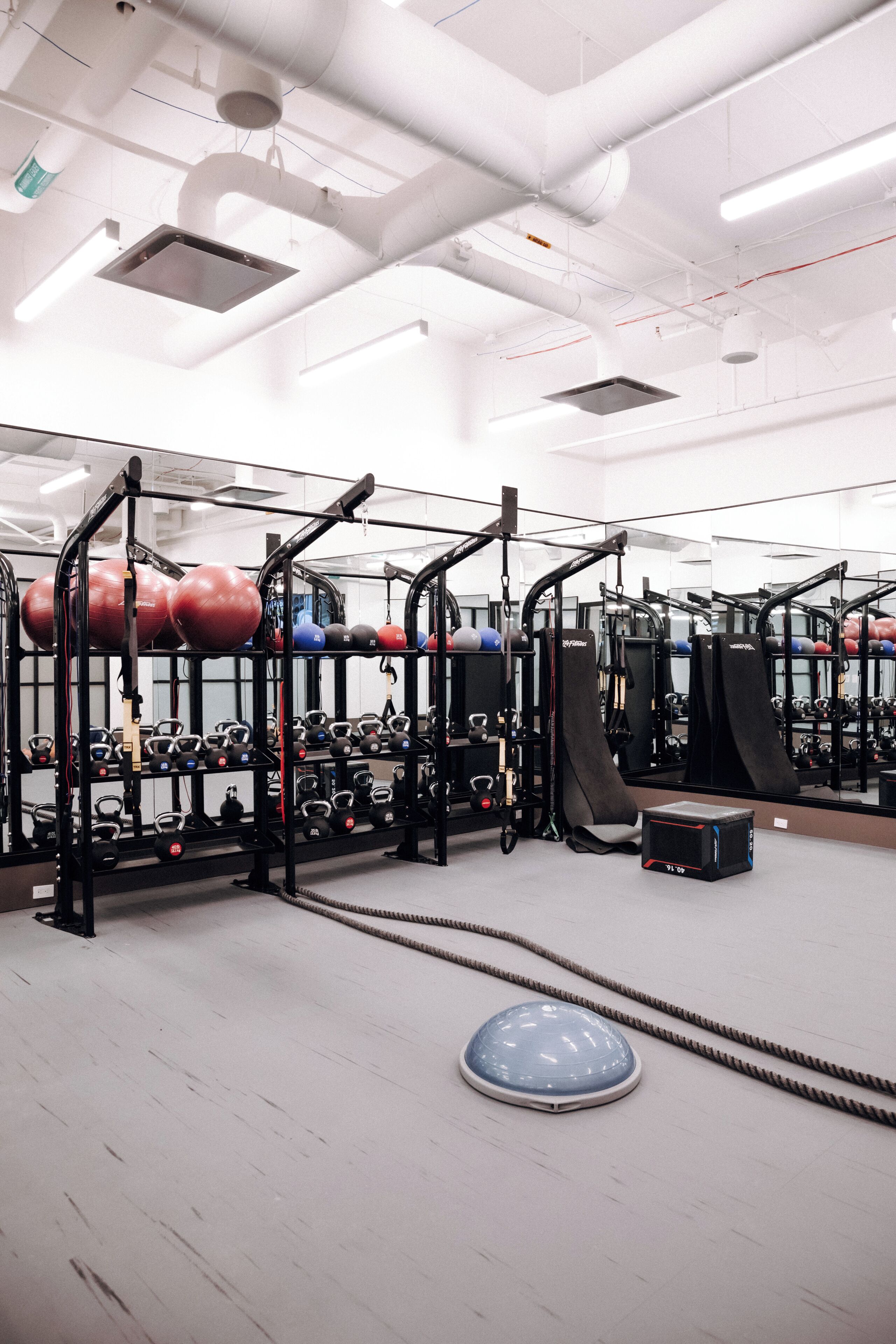 Une salle de sport équipée de matériel d’exercice, de supports pour les poids et d’un mur recouvert de miroirs.