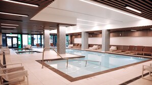 A modern indoor pool area with multiple lounge chairs and a diving board. - Level Seattle Downtown - South Lake Union (Seattle)