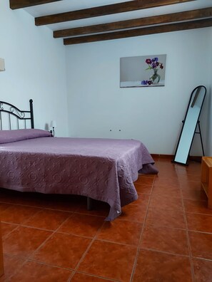 A bedroom with a bed, a nightstand, a lamp, a framed picture on the wall, and a mirror leaning against the wall. - Casa Benito Fagajesto (GALDAR)