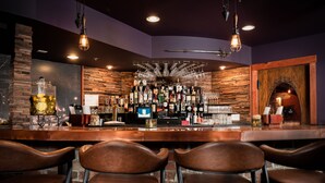 A bar area with wooden walls, a brick column, and leather chairs. - The Horton Hotel and Rooftop Lounge (Boone)