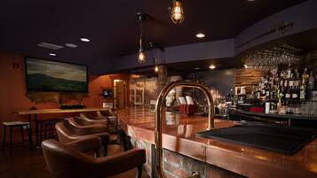 A bar area with leather bar stools, a copper bar counter, and a brick wall.