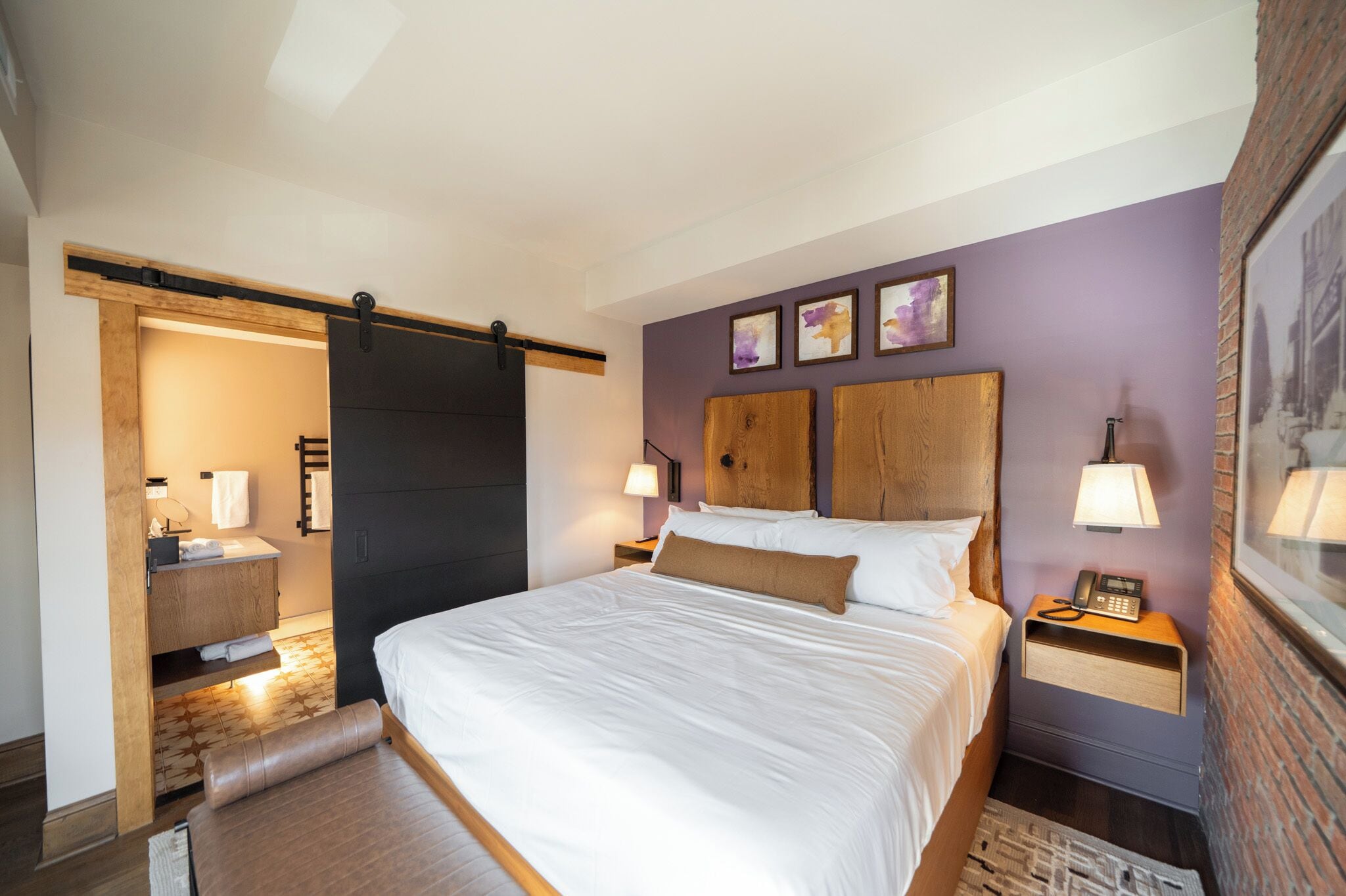 A modern bedroom with a large bed, wooden headboard, and two bedside tables with lamps.