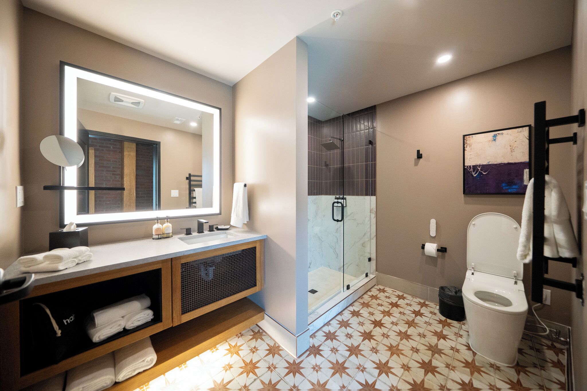 A modern bathroom with a vanity, mirror, shower, and toilet.