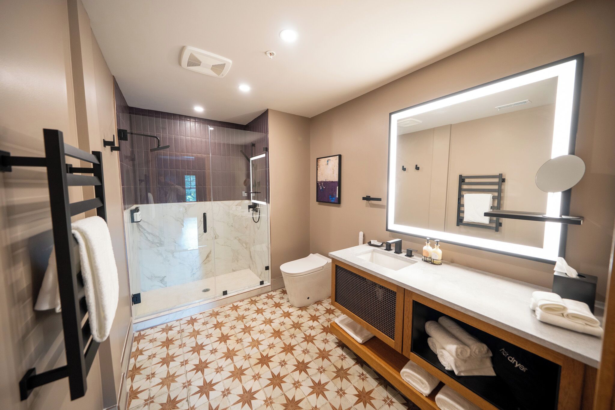 A modern bathroom with a glass-enclosed shower, a large mirror, and a vanity with a sink and towel rack.