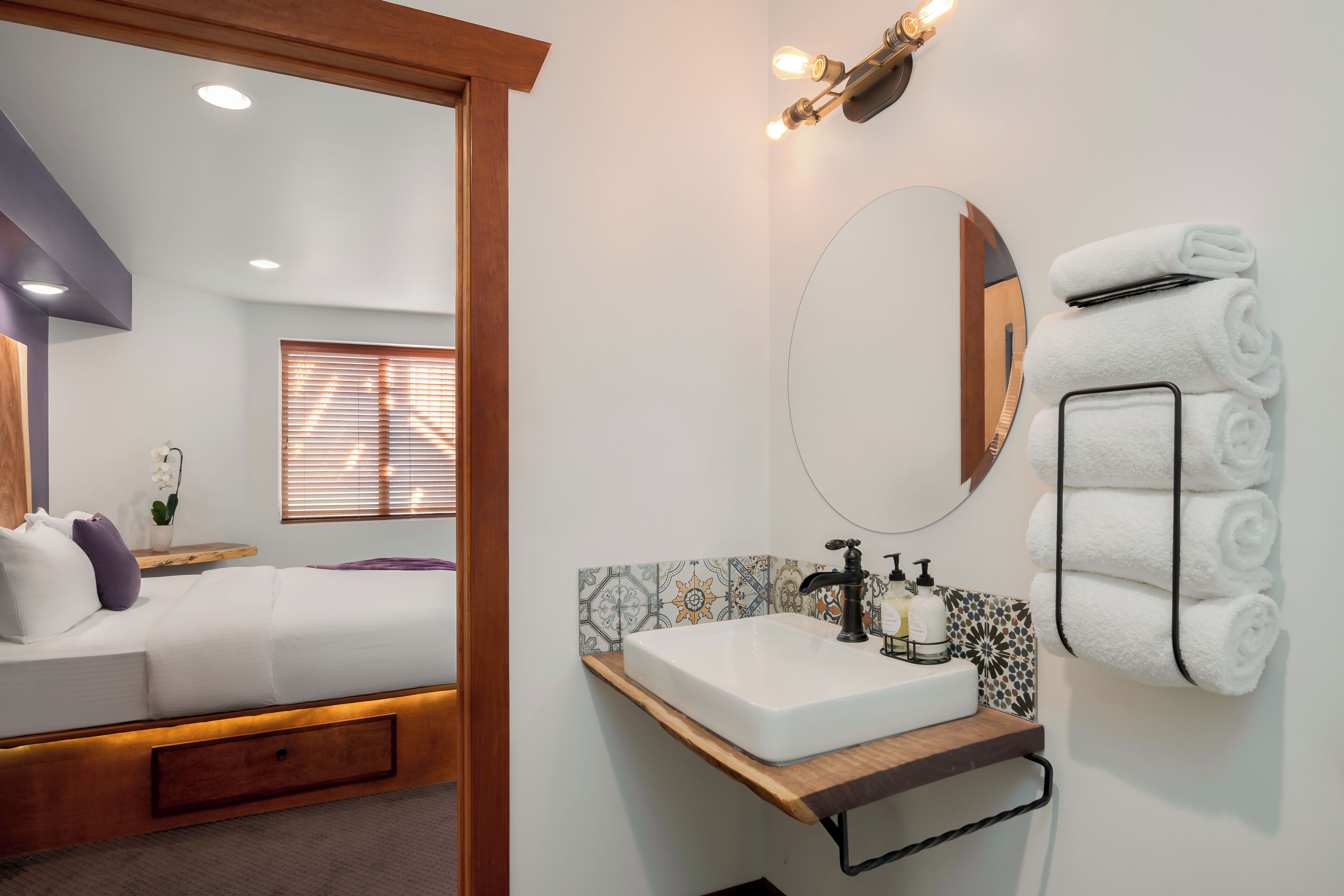 Une salle de bain moderne avec un lavabo blanc, un miroir et un porte-serviettes.