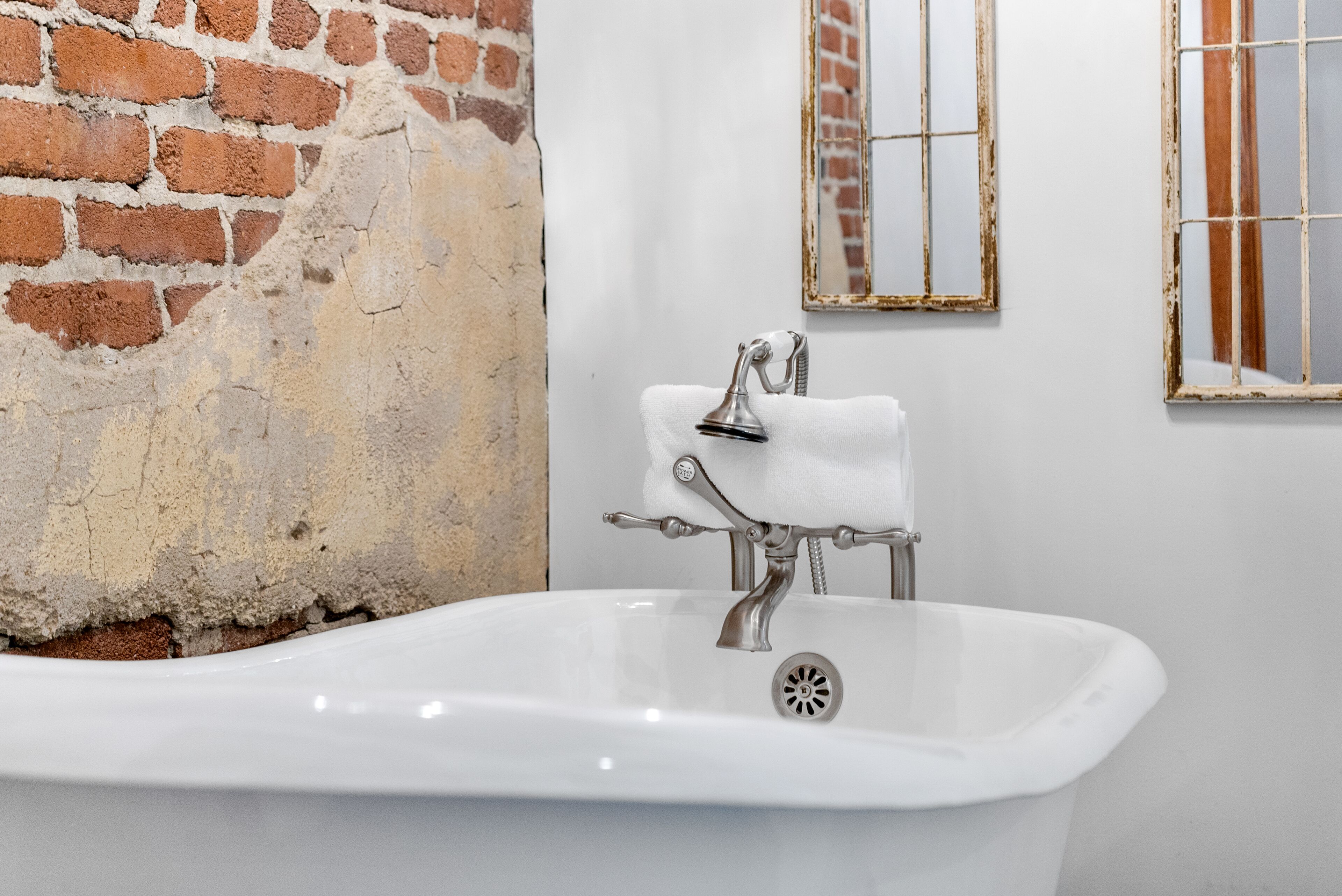 A bathroom with a white bathtub, a white towel, and a mirror with a wooden frame.