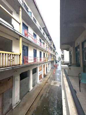 Un hotel de varios pisos con balcones, suelo mojado y barreras de construcción.