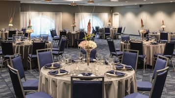 A conference room with round tables, chairs, and floral centerpieces.