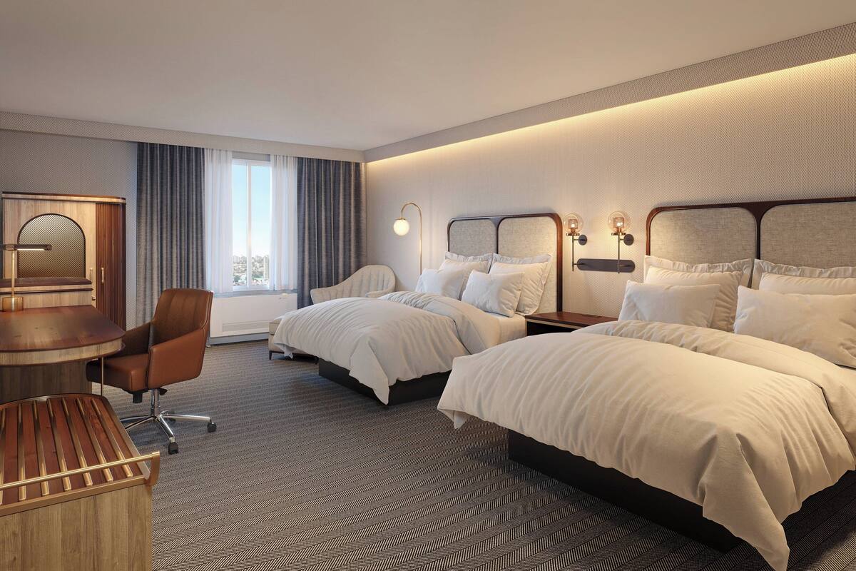 A hotel room with two beds, a desk, and a chair.