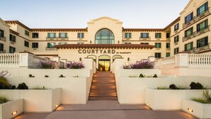 A multi-story hotel entrance with a central staircase, surrounded by planters and a sign reading "Courtyard by Marriott". - Courtyard by Marriott Santa Cruz (Santa Cruz)