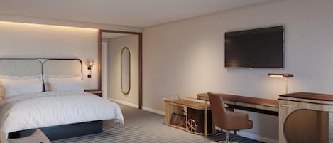 A modern hotel room with a large bed, a desk with a chair, a television, and a small seating area with cushions.