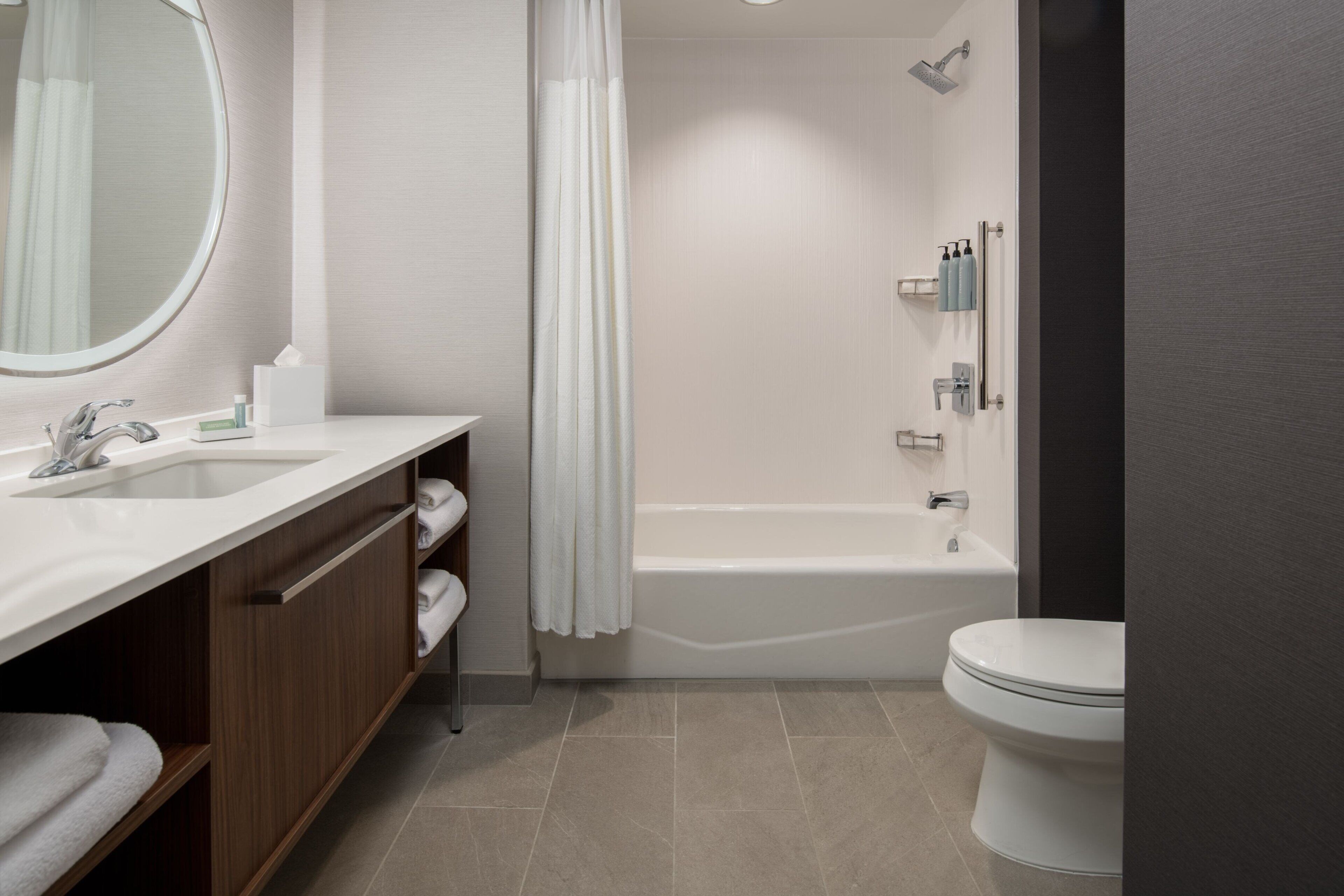 A modern bathroom with a sink, mirror, shower, and toilet.