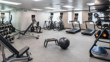 A gym with treadmills, elliptical machines, free weights, and exercise balls.