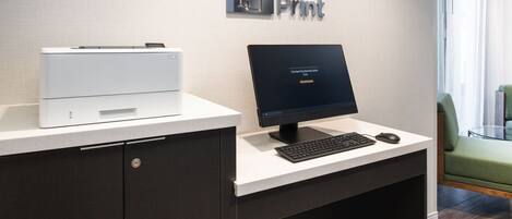 Un comptoir d’accueil équipé d’une imprimante, d’un écran et d’un clavier. Au-dessus du comptoir, on trouve une enseigne portant le nom « Quick Print », ainsi qu’une autre avec l’adresse et les numéros de téléphone.